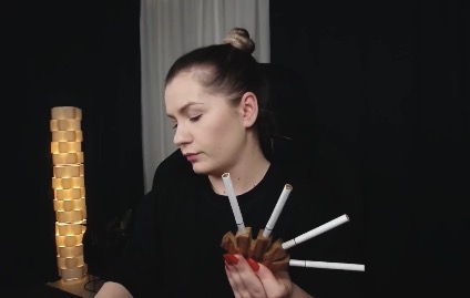 The girl smokes five cigarettes at once through a mouthpiece, taking deep drags